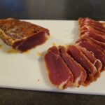 Filet mignon séché au poivre kampot et piment d'espelette sur une planche en plastique